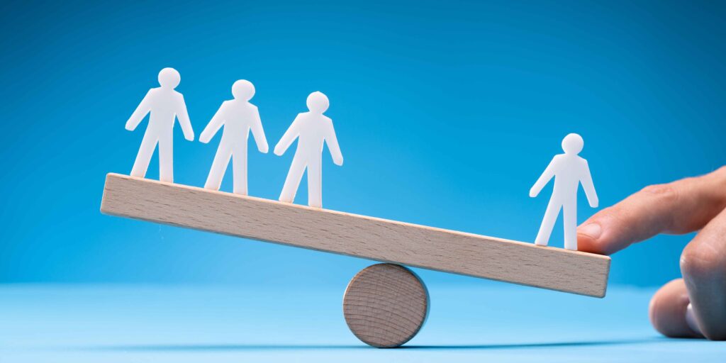 Image demonstrating prioritizing self over social comparison with one person on a balance scale as worth more/tipping the balance versus three on the opposite side
